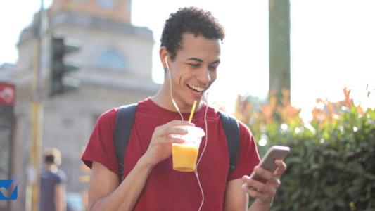 jeune homme écoutant de la musique et buvant un jus d'orange